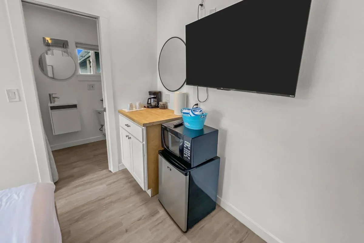 This image displays the kitchenette area with appliances like a microwave, coffee maker, and television, set within a casual and homey environment. The space feels practical yet inviting, perfect for preparing simple meals or enjoying a morning coffee while watching TV.
